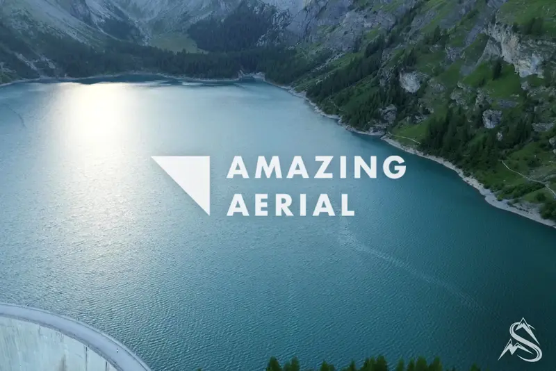 Aerial of the turquoise Lac de Tseuzier reservoir in the Swiss Alps, the Amazing Aerial mark overlaid